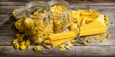 Dry pasta in cans and mixed the pasta with spaghetti. On wooden background.